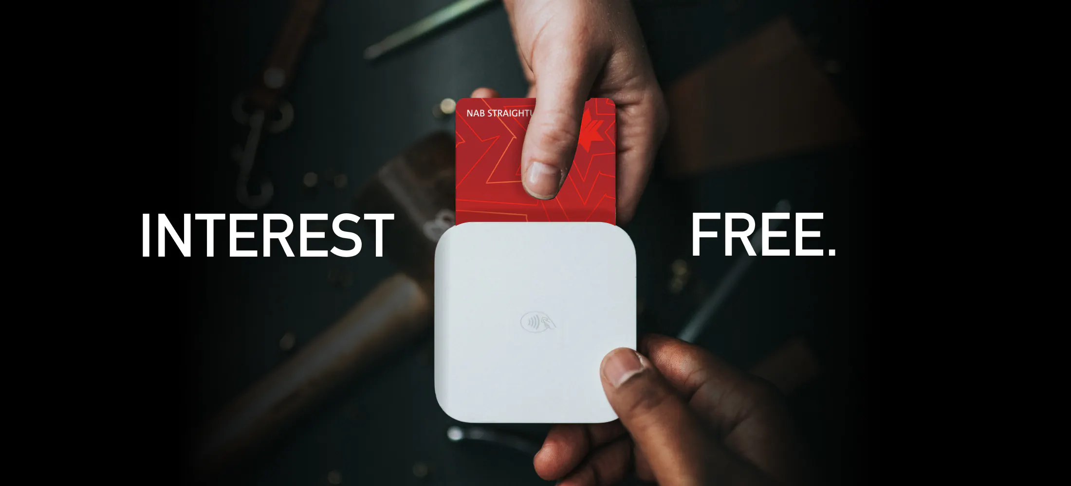 A red NAB StraightUp card being tapped on a white payment terminal held in another person's hands, captioned 'Interest free.'